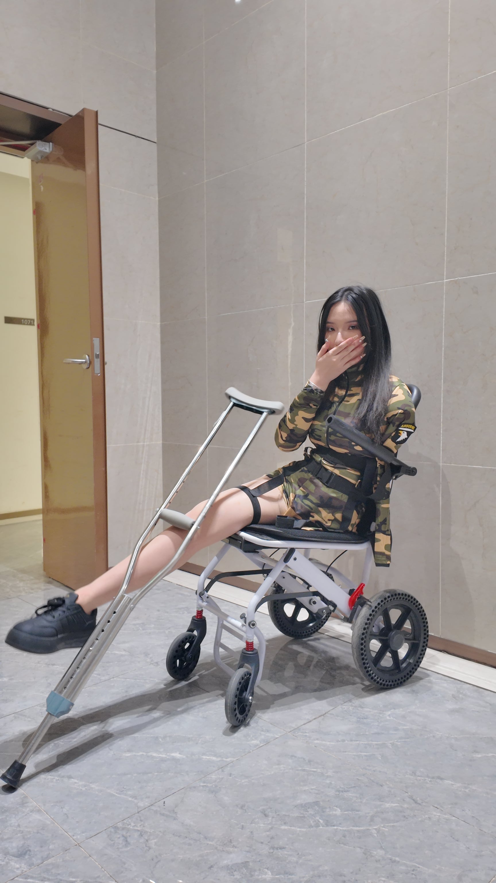 Beibei a Ooe Amputee Girl in camouflage outfit sitting in a wheelchair