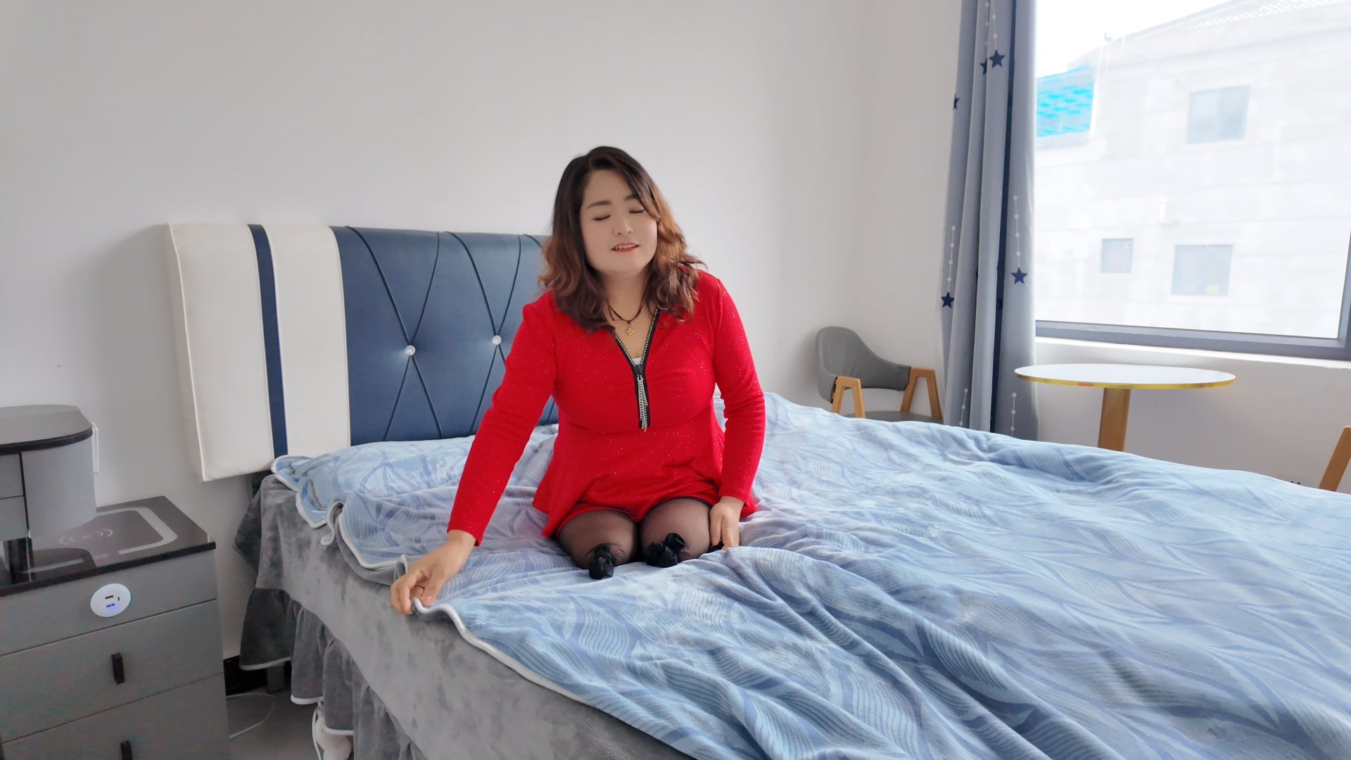 Tina, dressed in a red dress and wearing black, crawled on the bed.