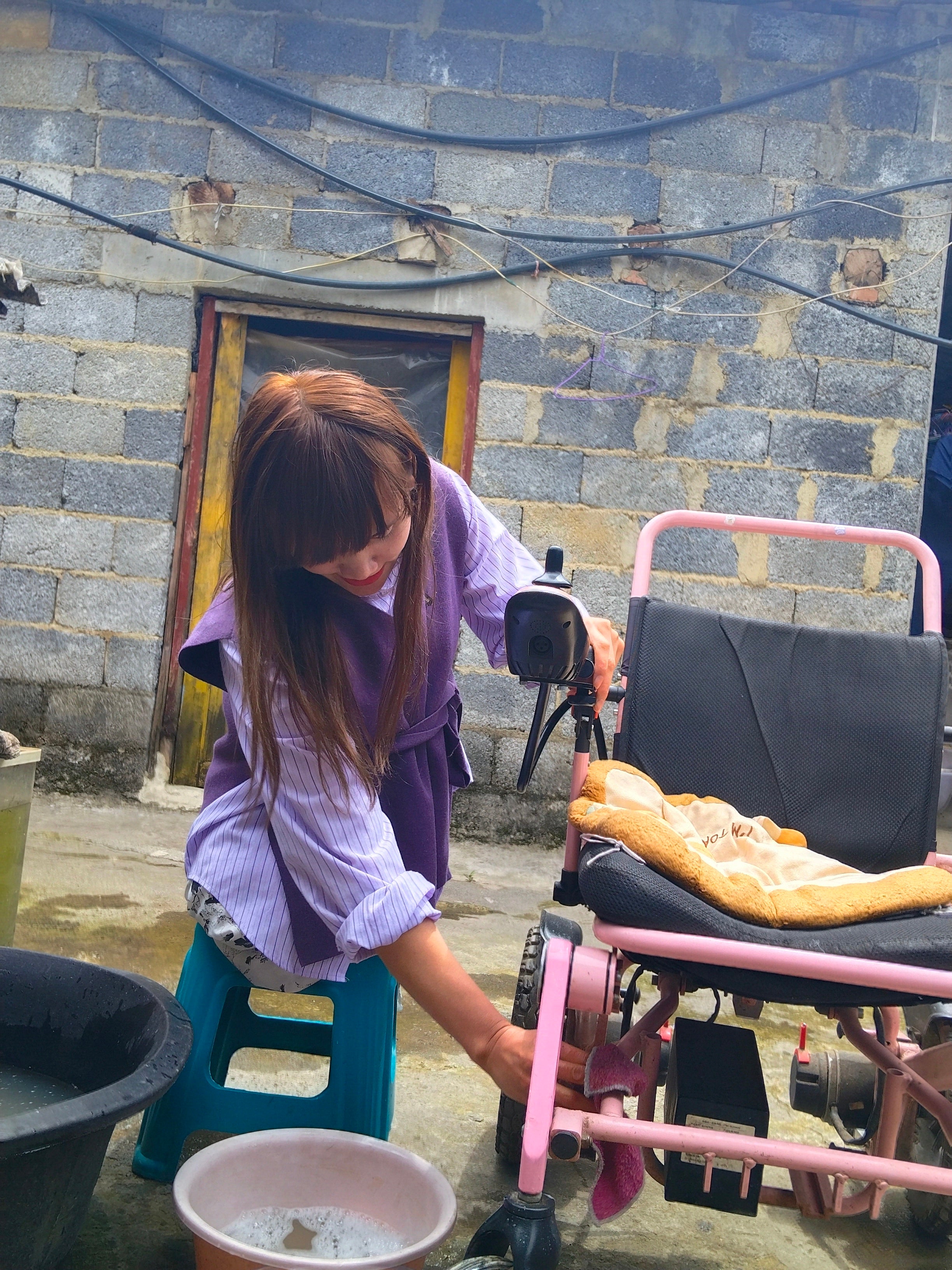 The DAK Girl, Lvy — Sitting on a Bench, Cleaning a Wheelchair