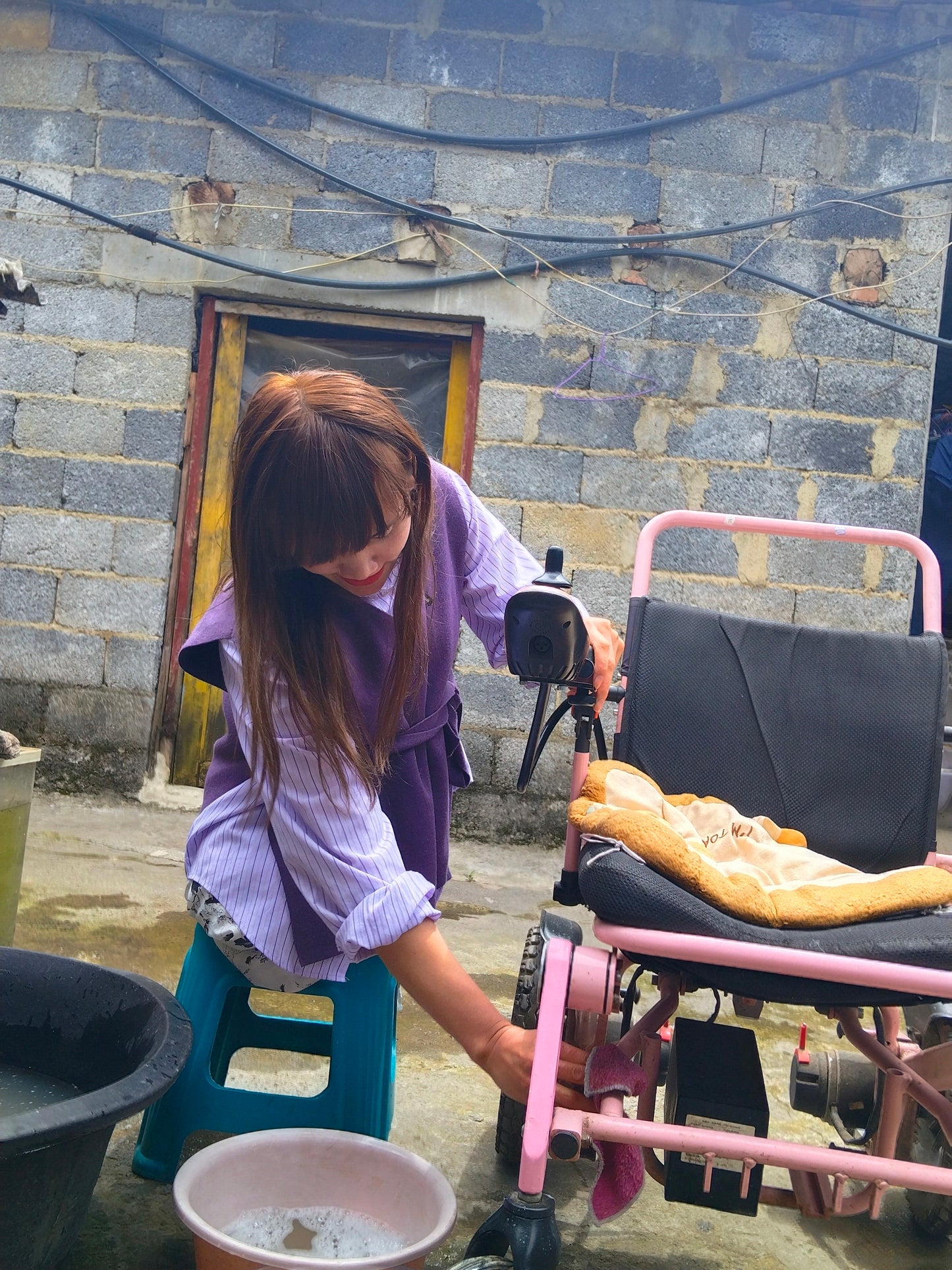 The DAK Girl, Lvy — Sitting on a Bench, Cleaning a Wheelchair