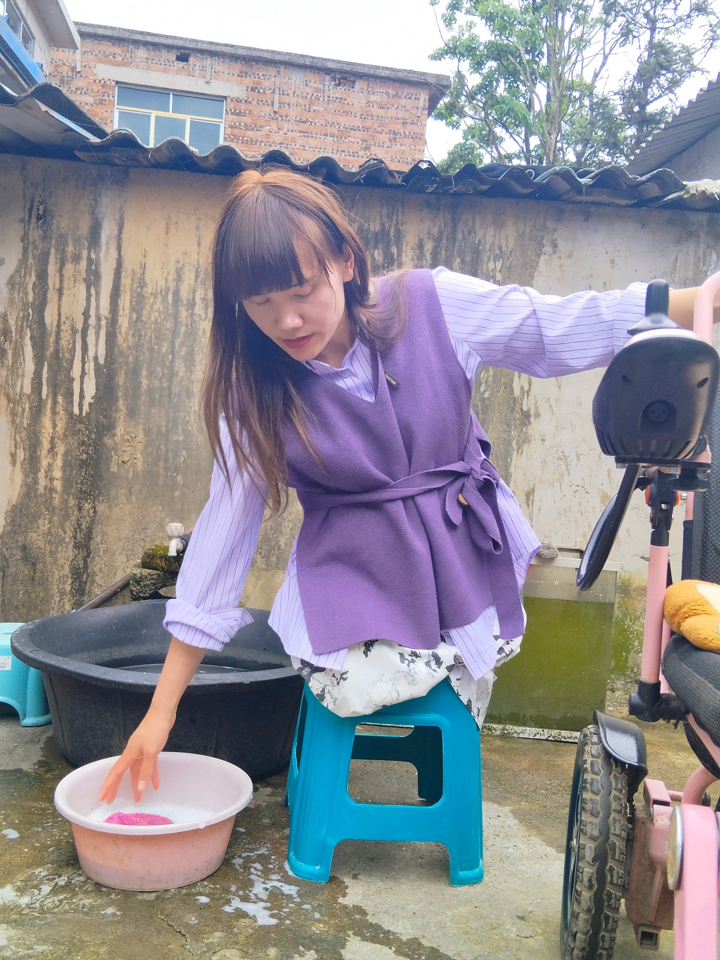 The DAK Girl, Lvy — Sitting on a Bench, Cleaning a Wheelchair